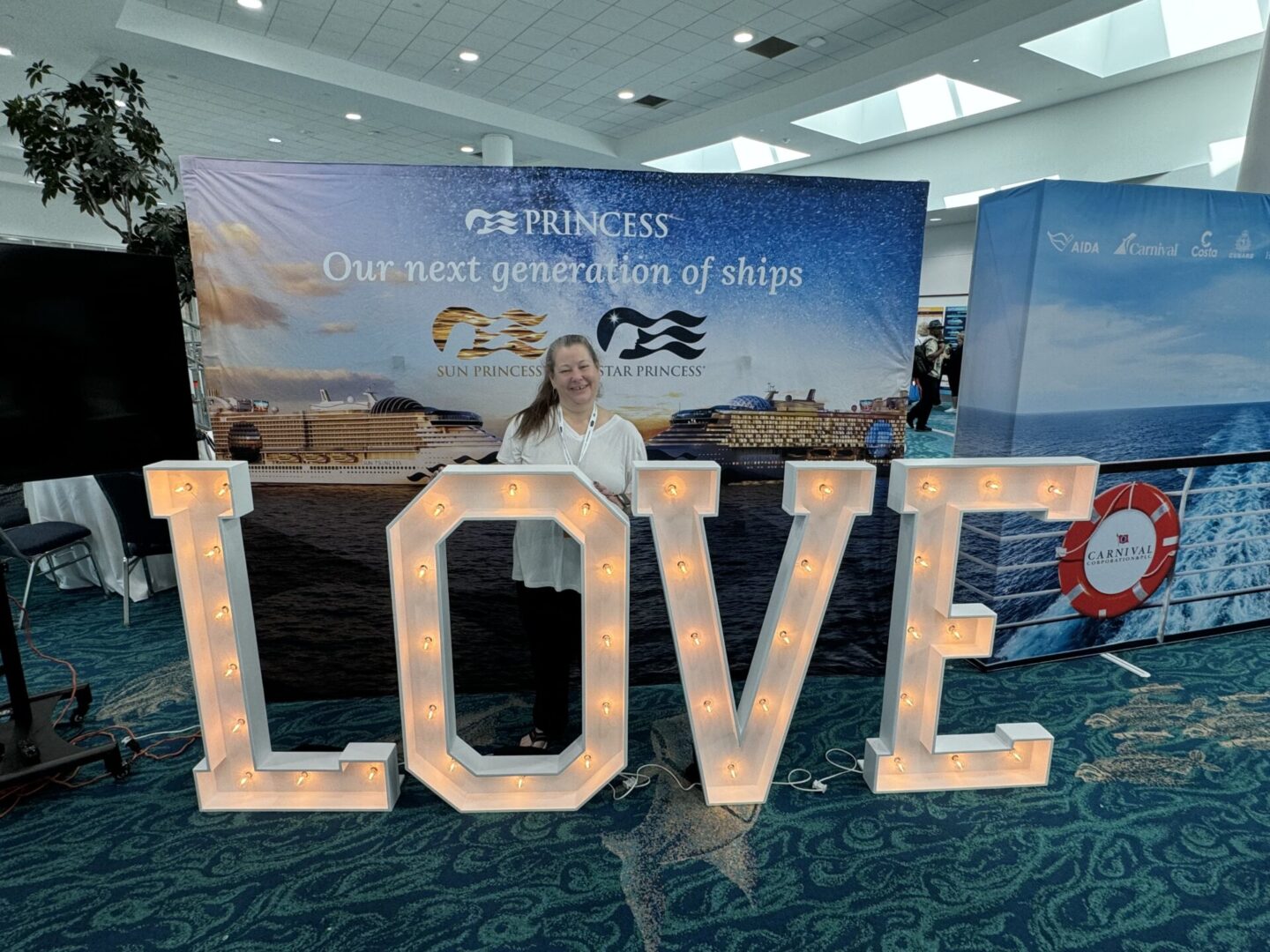 A woman standing next to a large love sign.