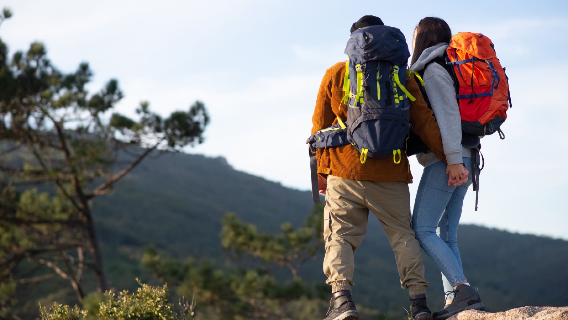 Two people with backpacks walking on a trail.