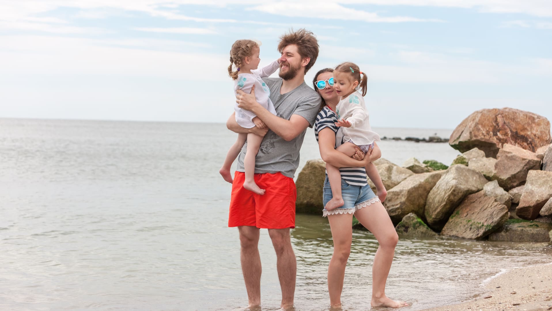 A man and two children are standing on the beach.