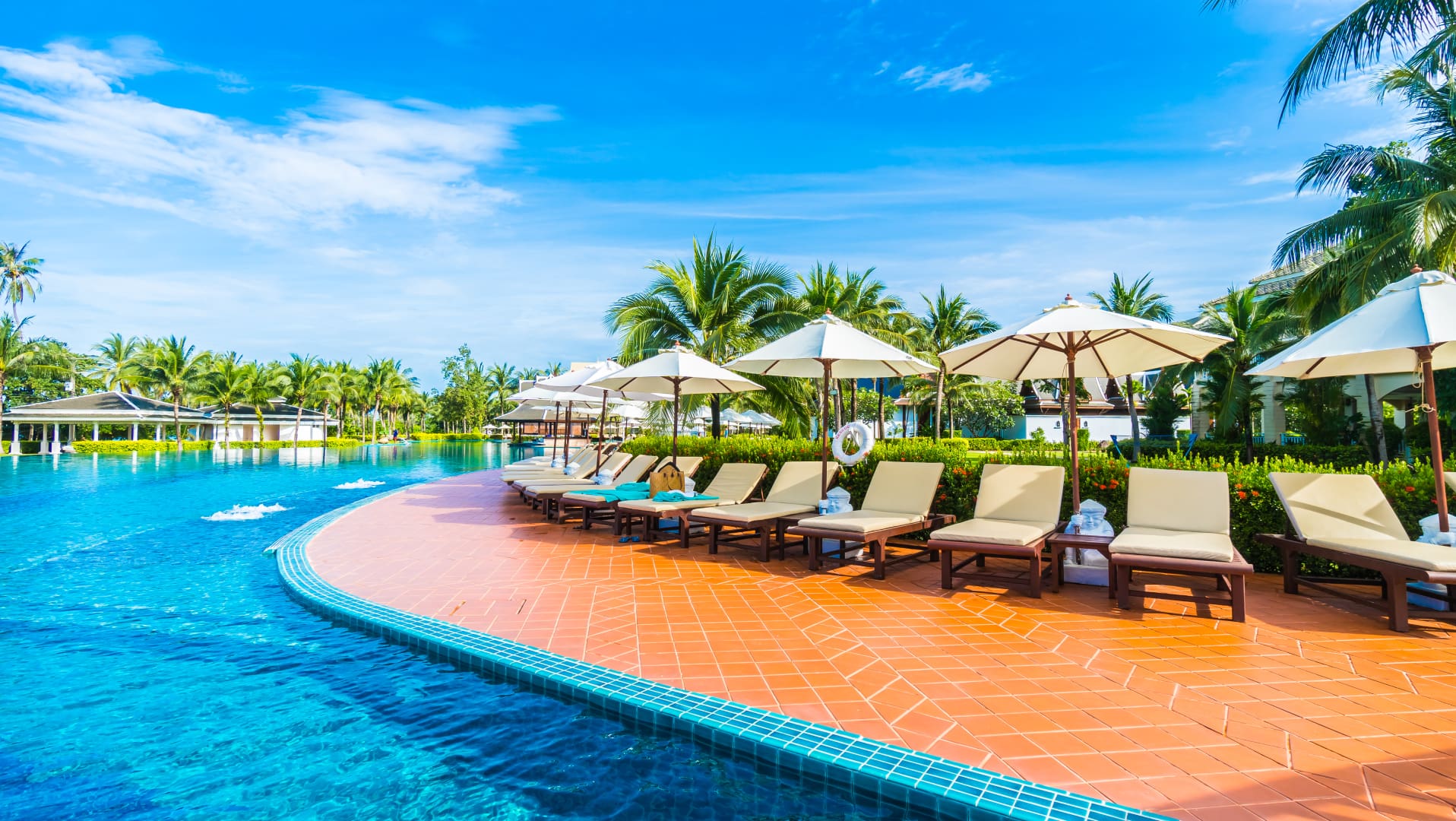 A pool with many chairs and umbrellas next to it