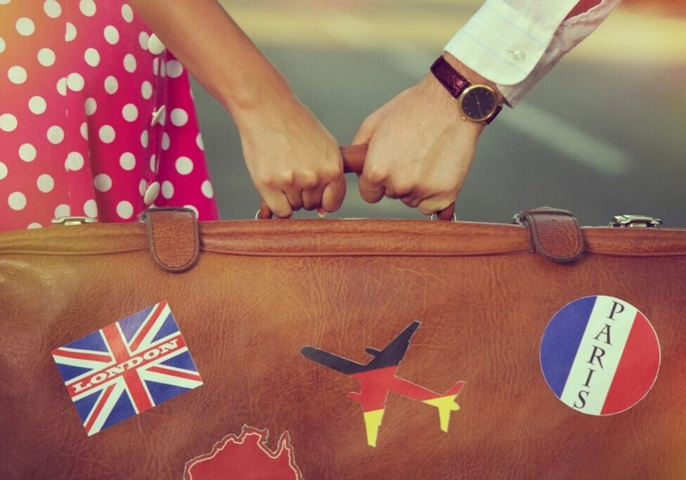 A close up of two people holding hands on top of a suitcase