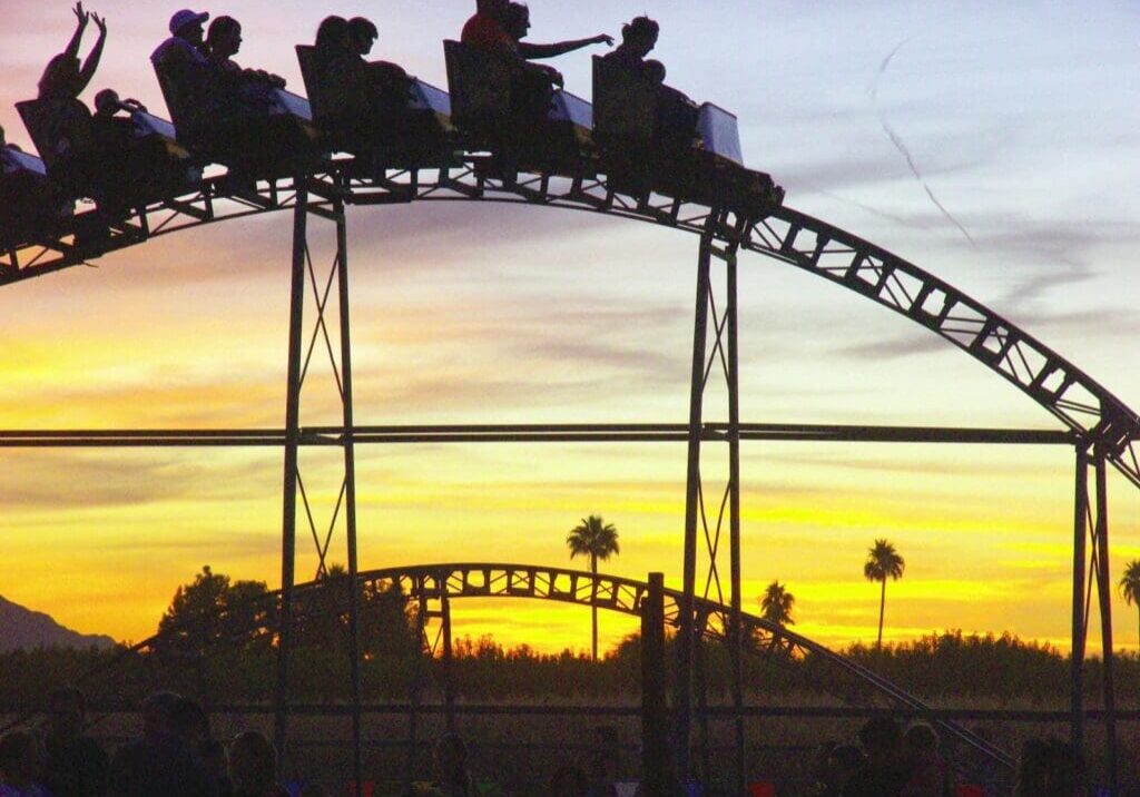 A roller coaster with people riding it at sunset.